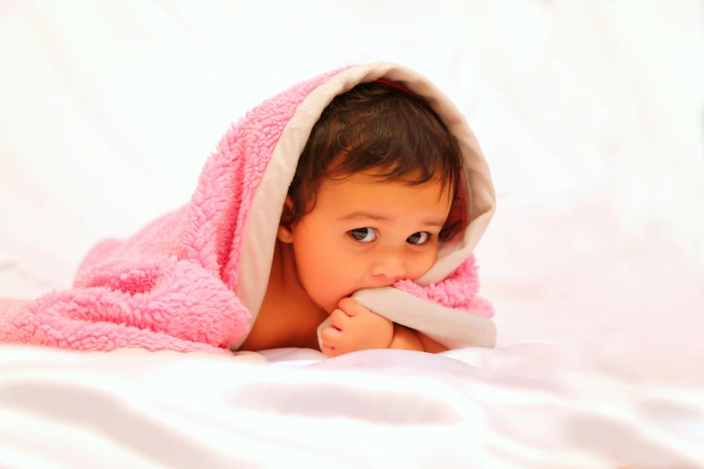 a little girl lying under a blanket looking out
