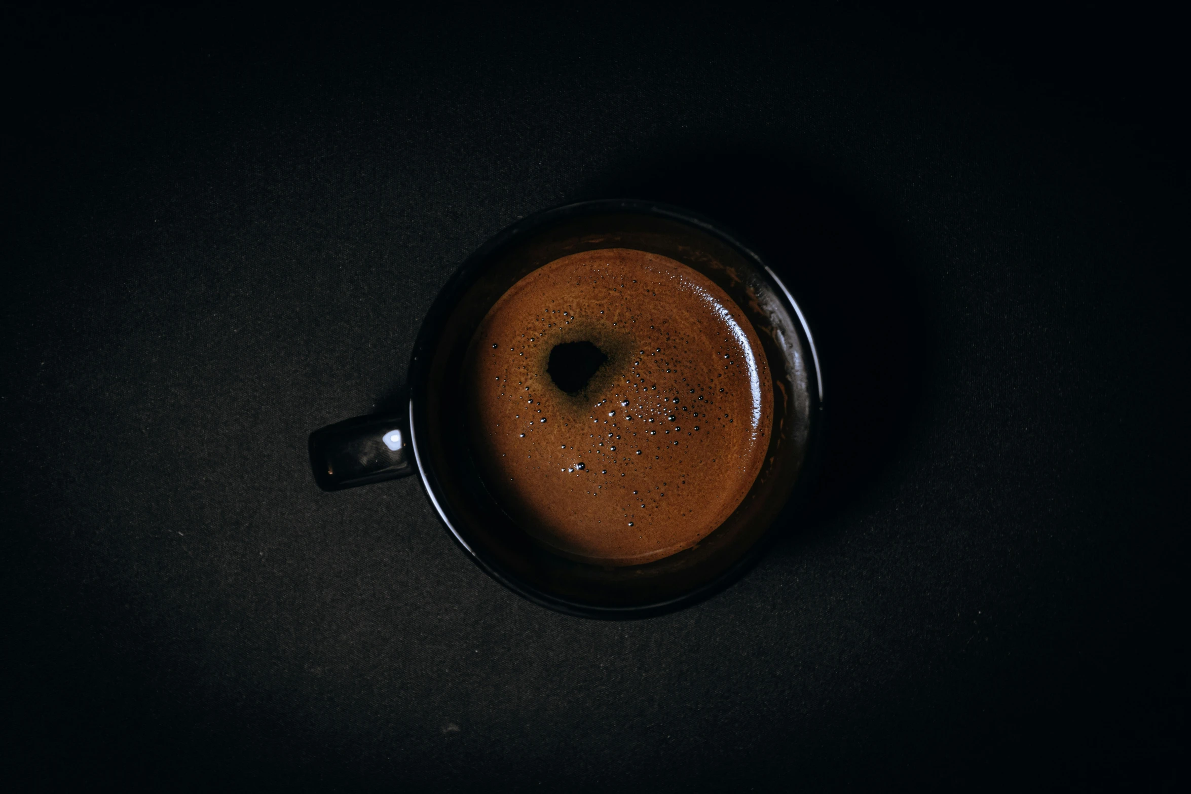 a small mug of liquid sitting on top of a black surface