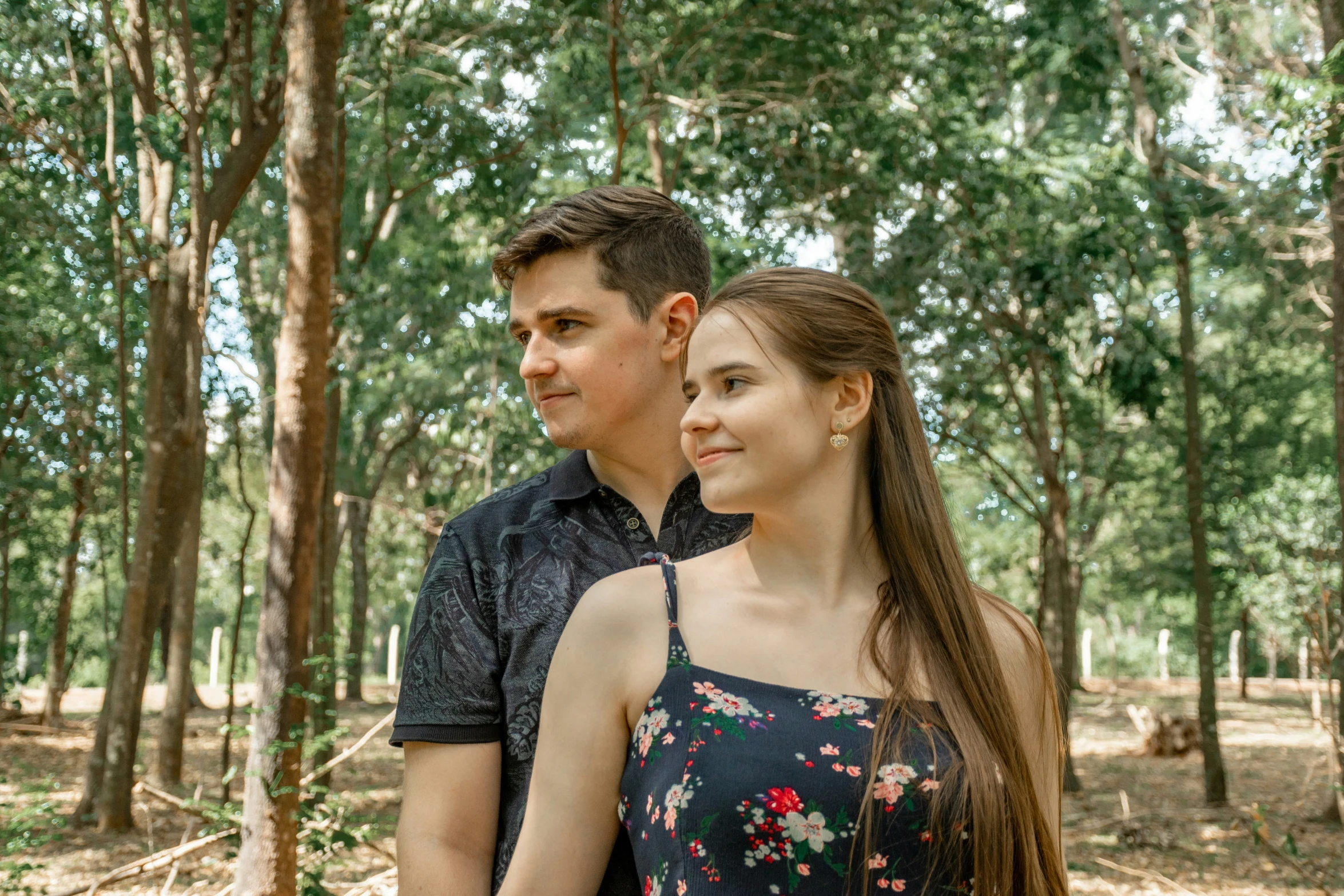 a man standing next to a woman in a forest