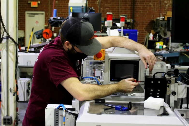 man in red shirt working on a machine