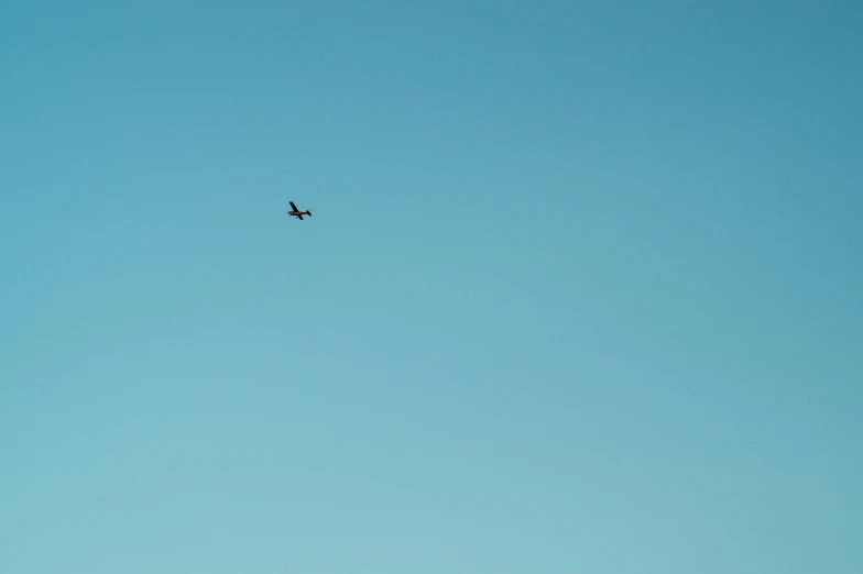 an airplane is flying high above in a light blue sky