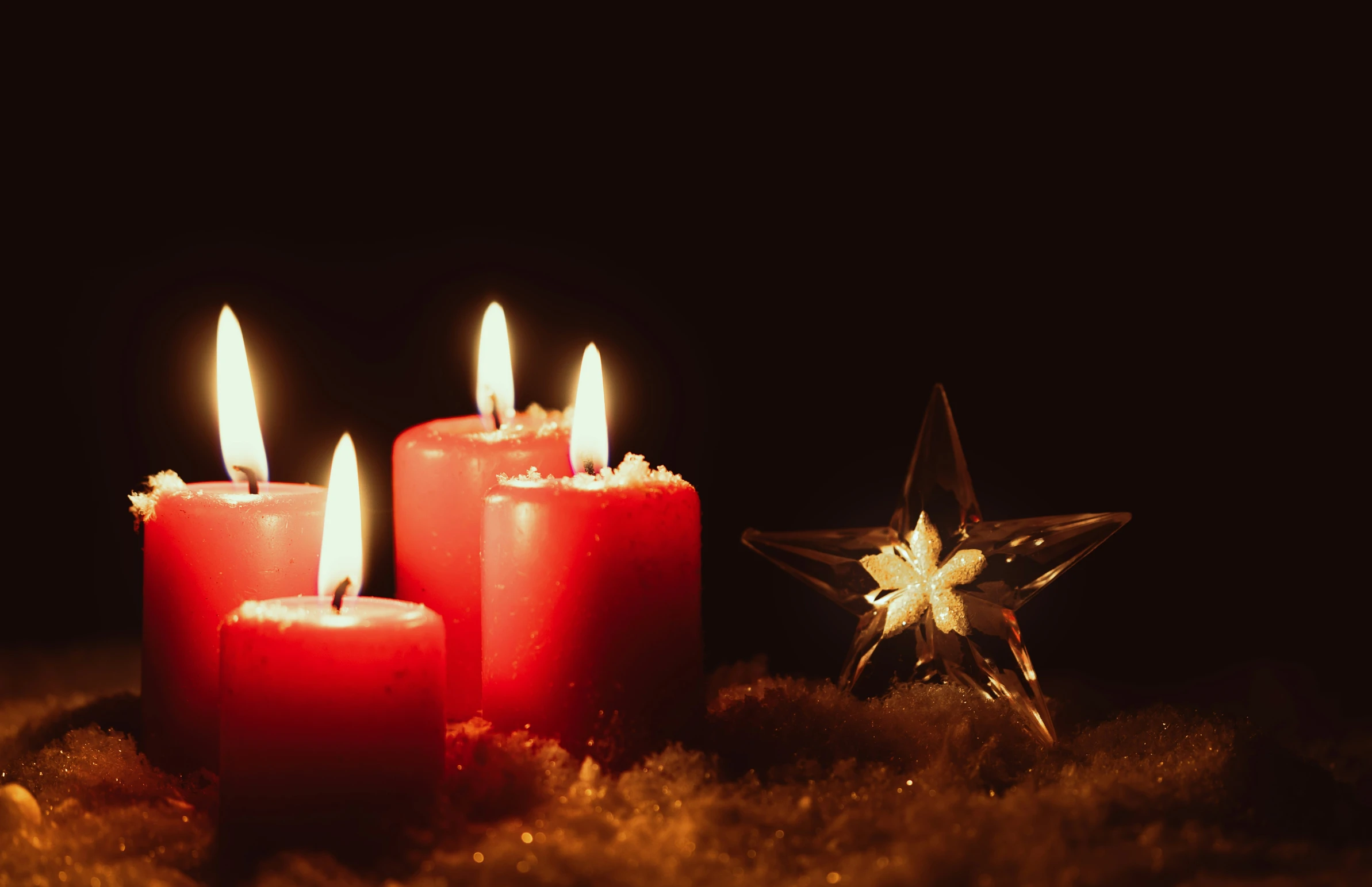 three lighted candles sit near a star and a sparkler