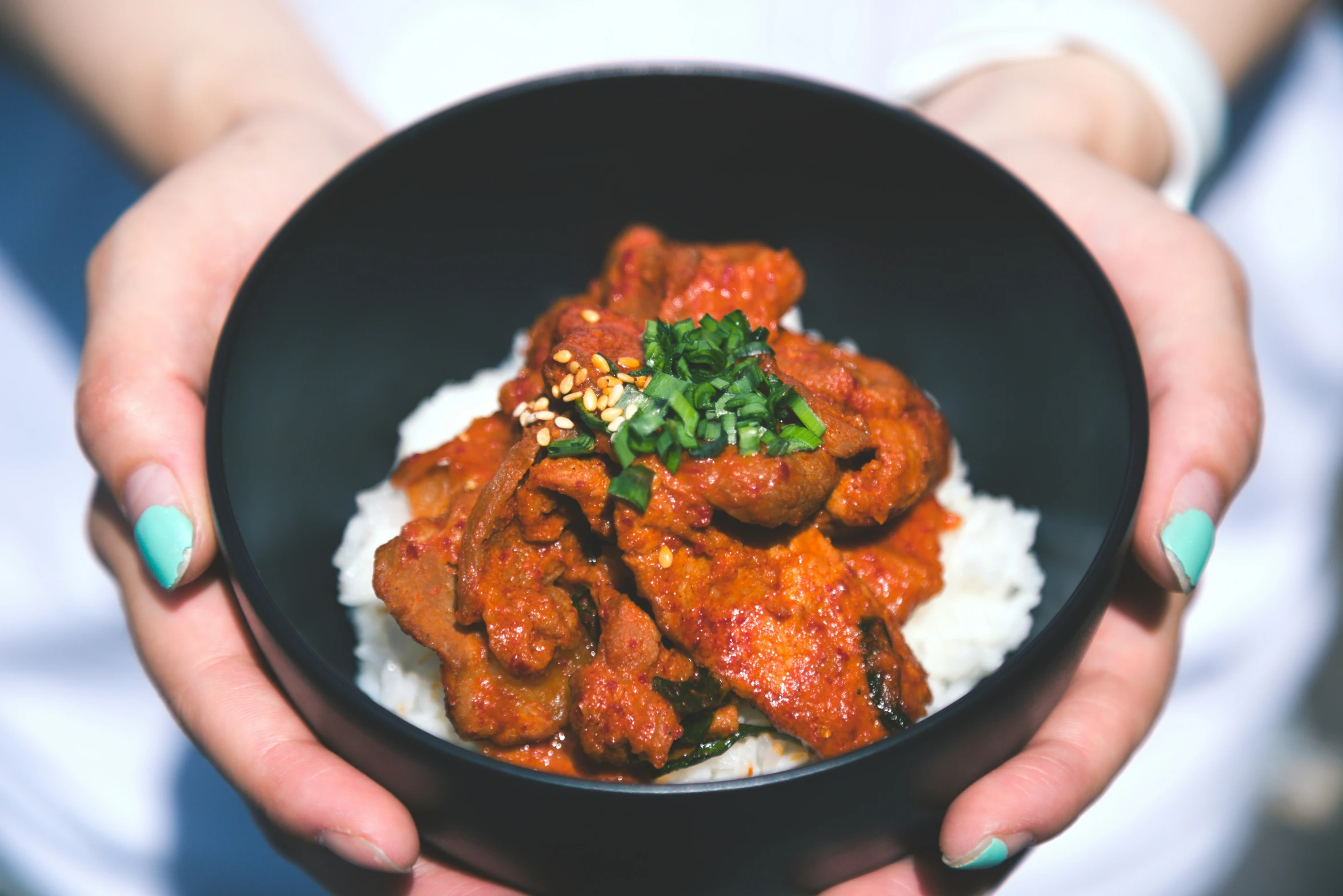 a woman holding a bowl filled with meat and rice