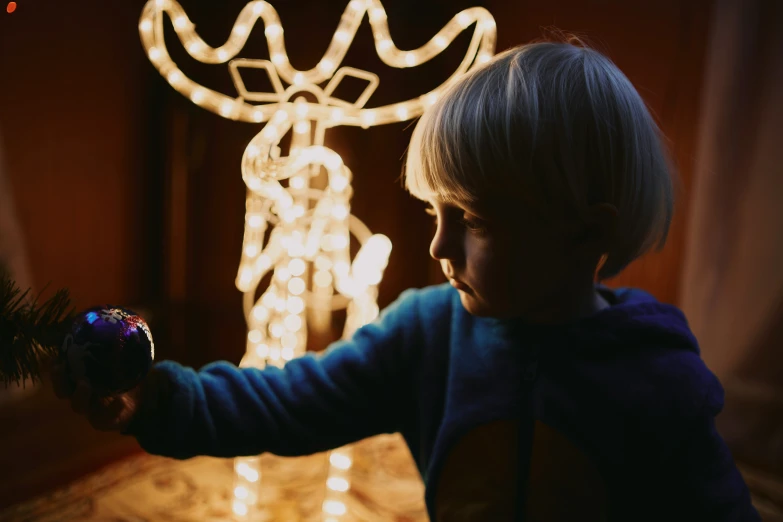  playing with lighted ornaments in front of a reindeer