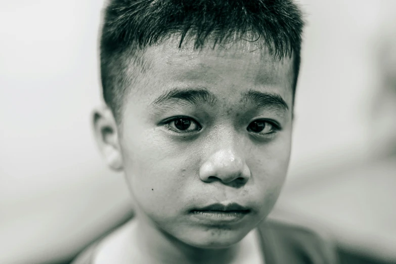 a small boy with black hair is dressed in a suit