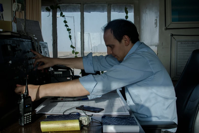 a man sitting at a desk working on an old radio