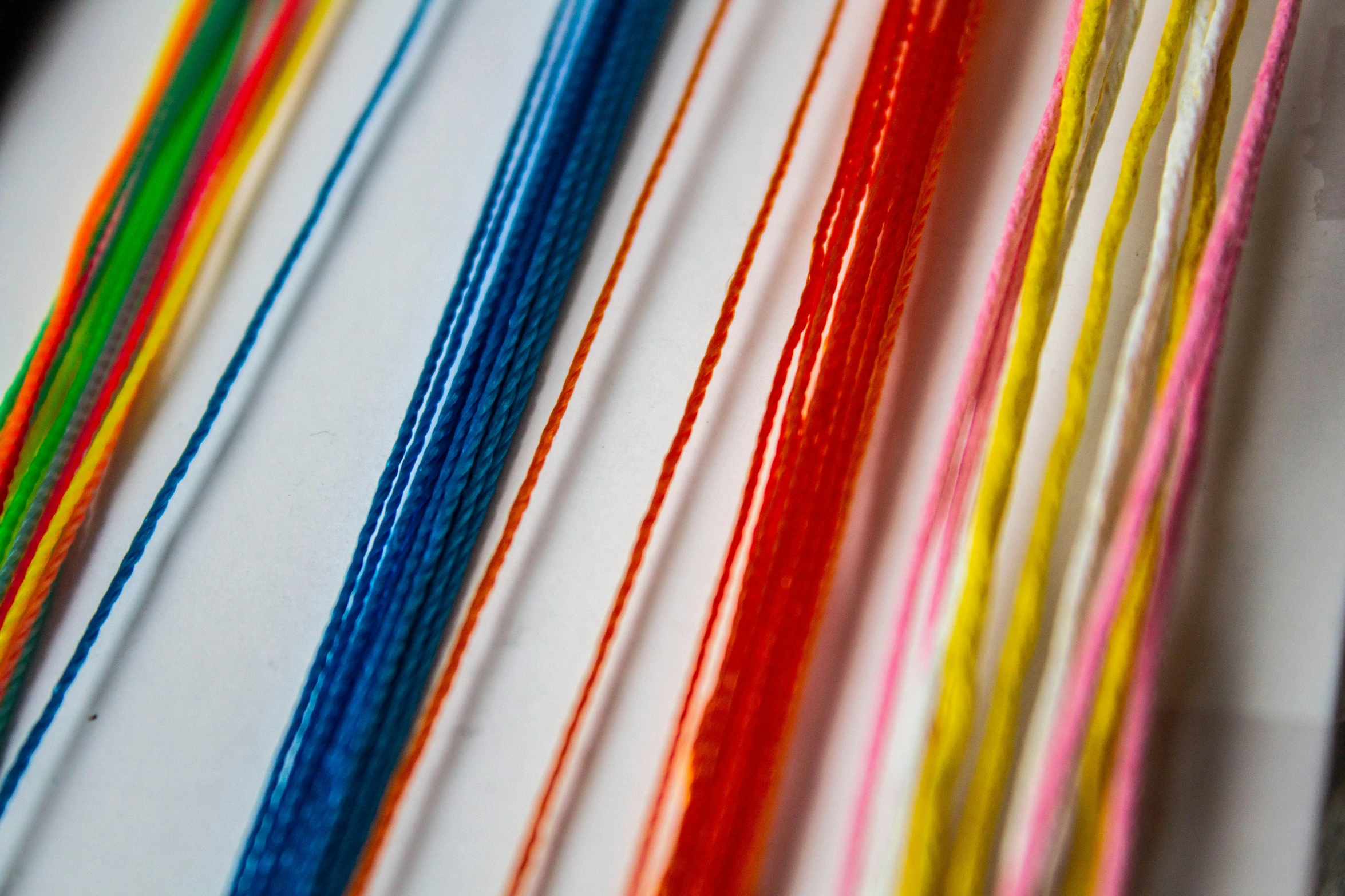 a row of colorful threads on a white surface