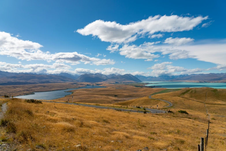 a valley with brown grass and water in the background