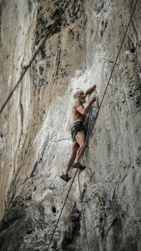 a shirtless man is on a rock climbing