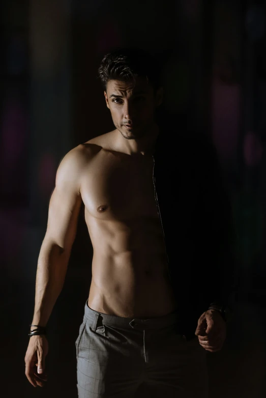 a young man without a shirt in front of a black background