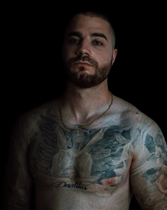 man with a dragon tattoo on his chest looks up into the sky