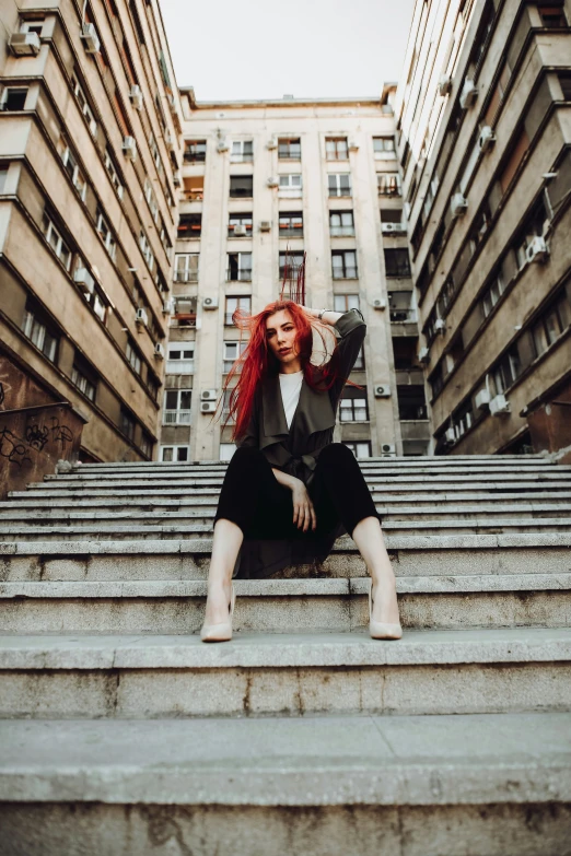 a woman sitting on some stairs in front of tall buildings