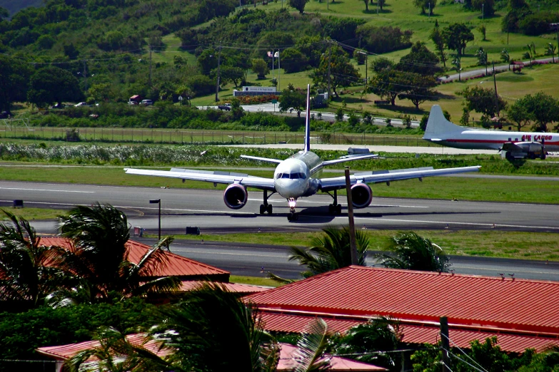 an airplane taking off from the runway near a park