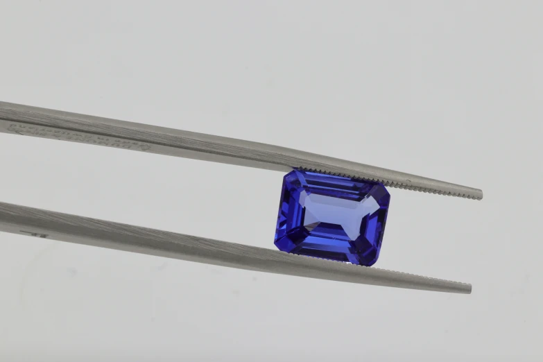 a diamond cut sapphire on a pair of tongs