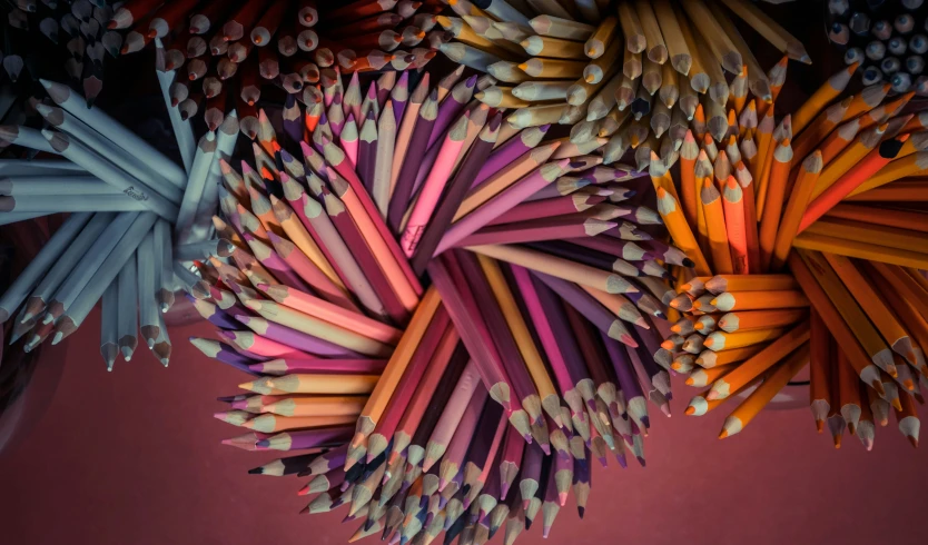 many different colored pencils arranged in a triangle
