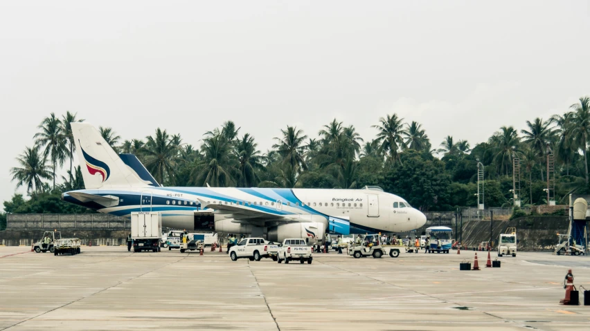 large white airplane with blue stripes is being serviced