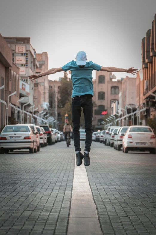 a young man standing on top of a sidewalk in front of parked cars