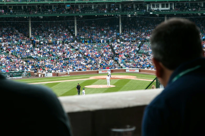 baseball players and fans watch as their pitcher prepares to throw the ball