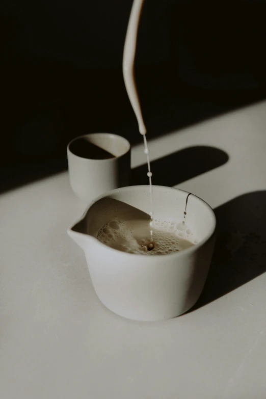 water is poured into white bowls with spoons in it