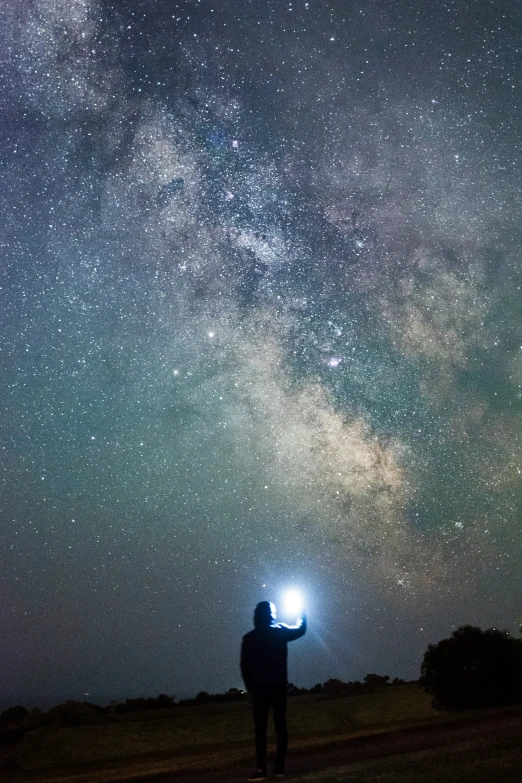 a man with a flashlight looking up at the sky