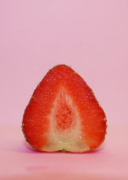 a red strawberry with green seeds and pink background