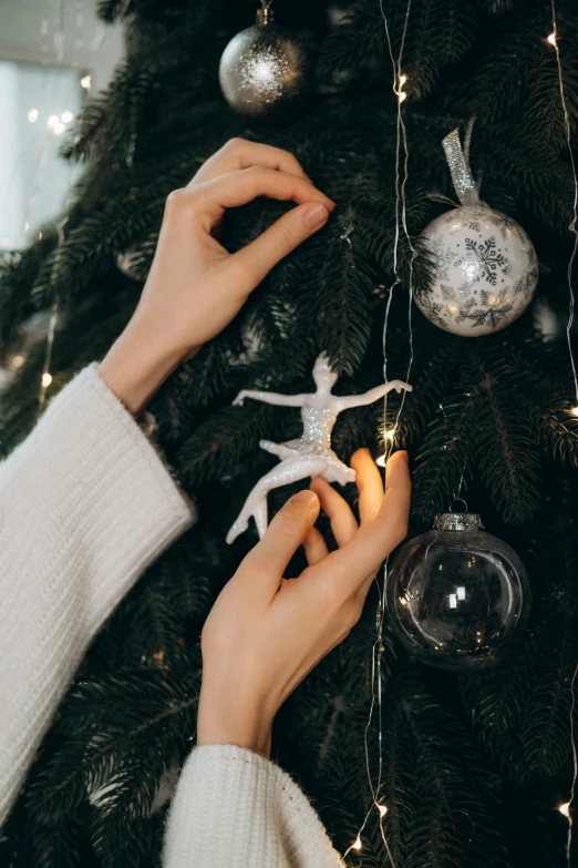 a person decorating a christmas tree with a silver star ornament