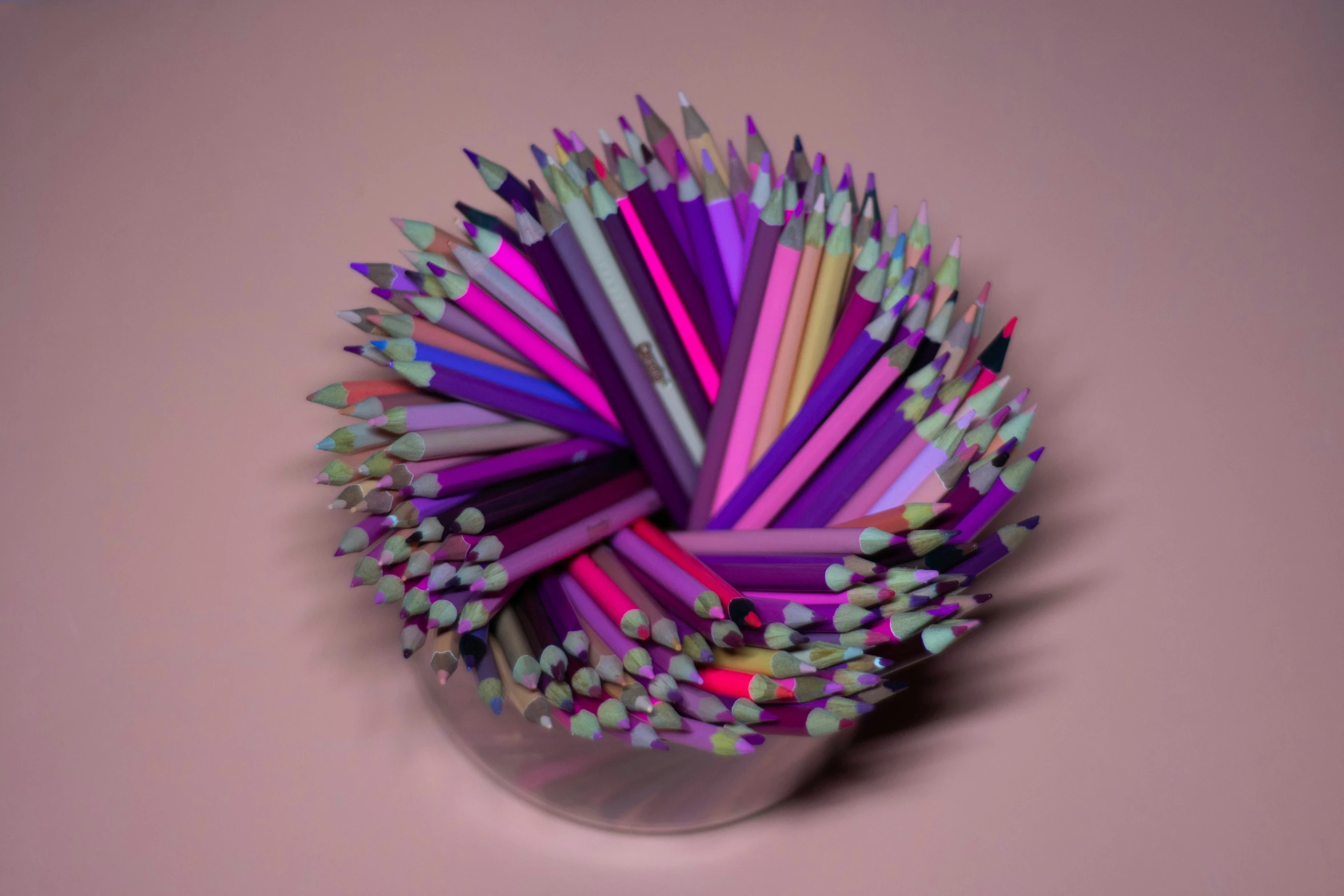 colored pencils laying on a table in a glass container