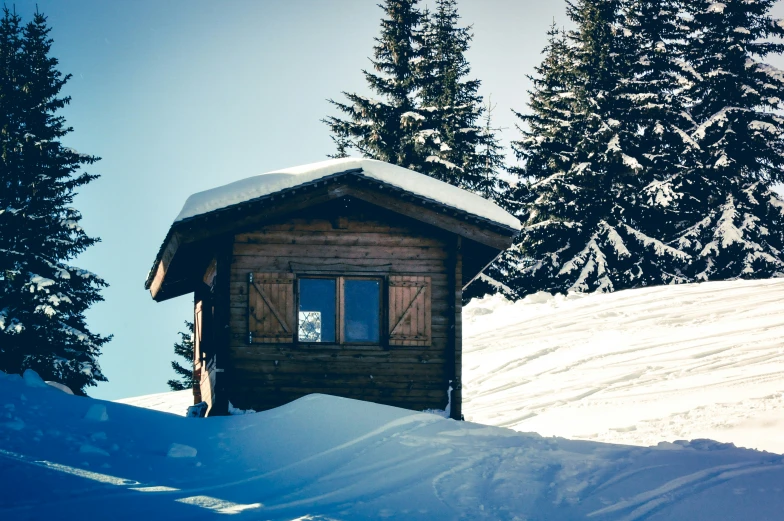 a small house sitting on top of a snow covered slope