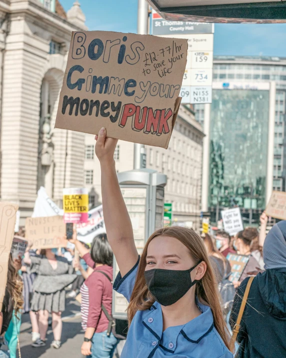 a woman with a mask holds up a sign in the air