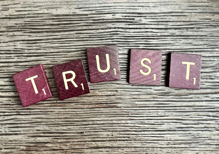 trust spelled with cut out letters on top of wood
