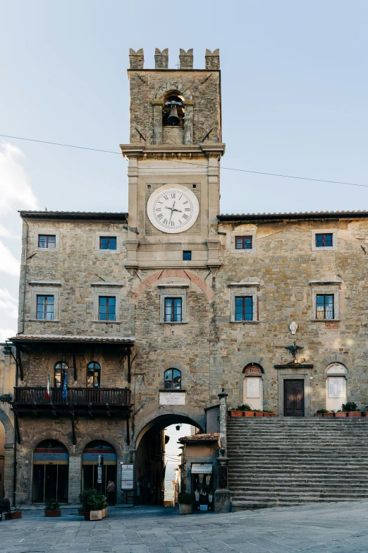 a stone building with a clock on the front and side