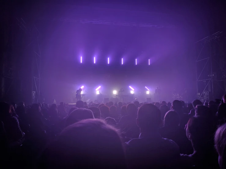 a dark stage with the lights on and people standing in front