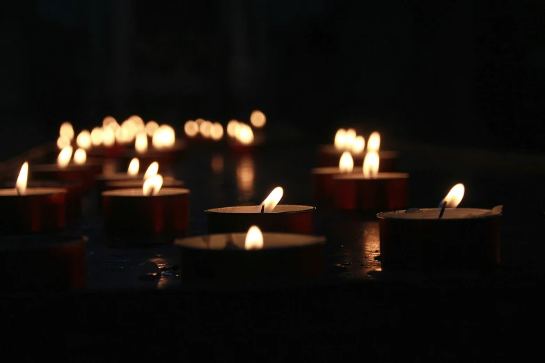 many red candles sit on a black surface