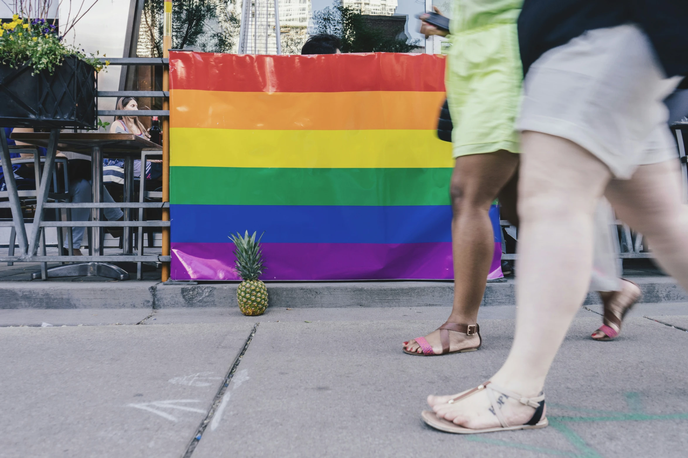 the people are walking past the rainbow flag