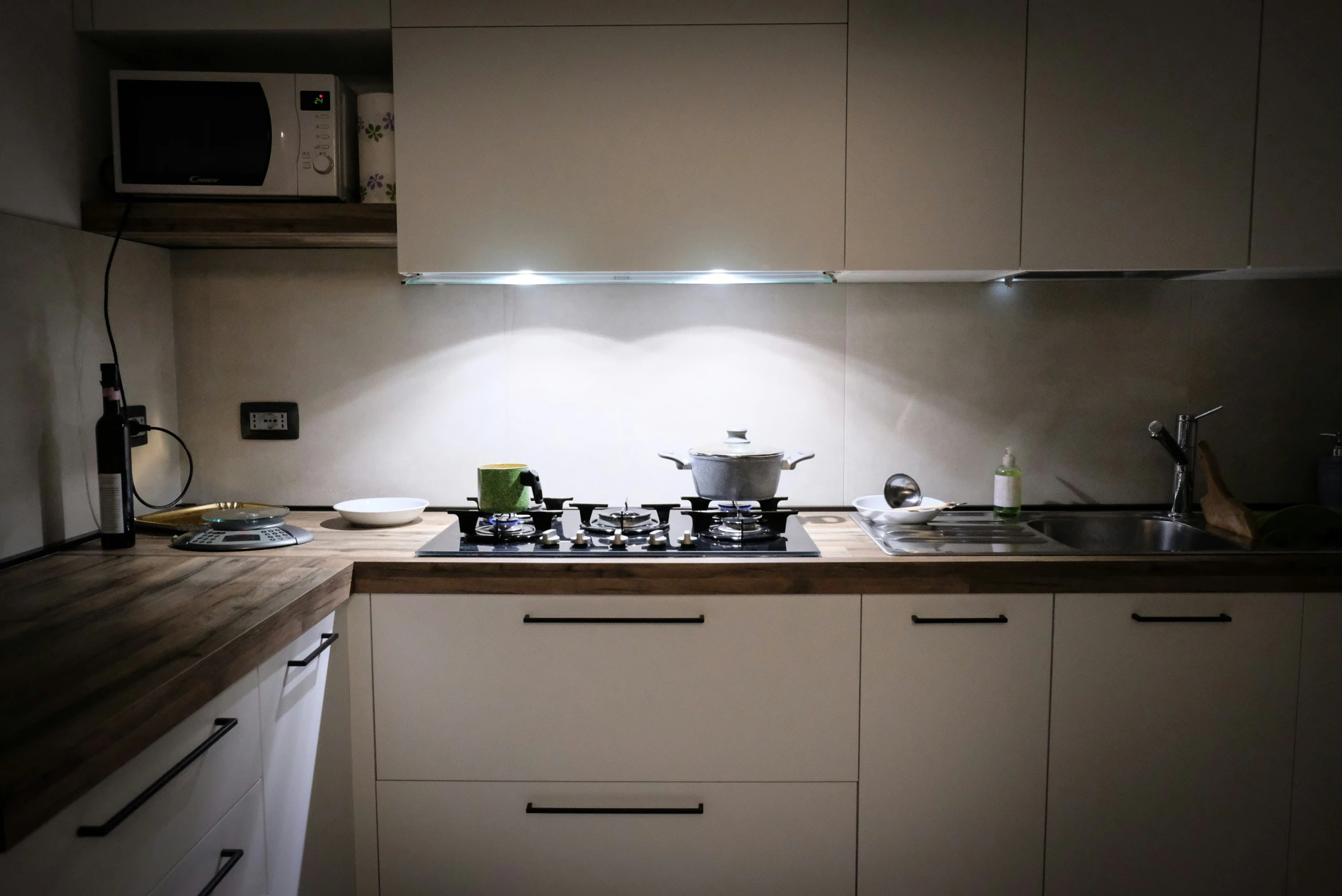 a kitchen with white cabinets, wood counters and pots and pans