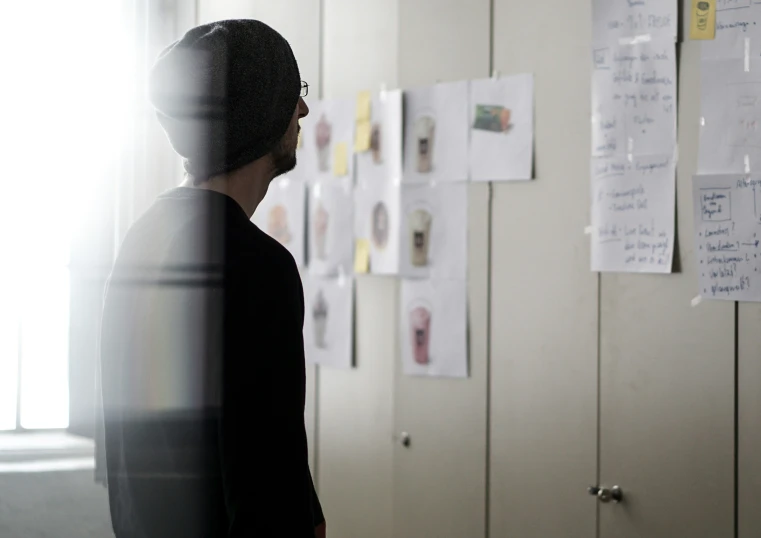 a woman looking at a wall with many notes hanging on it