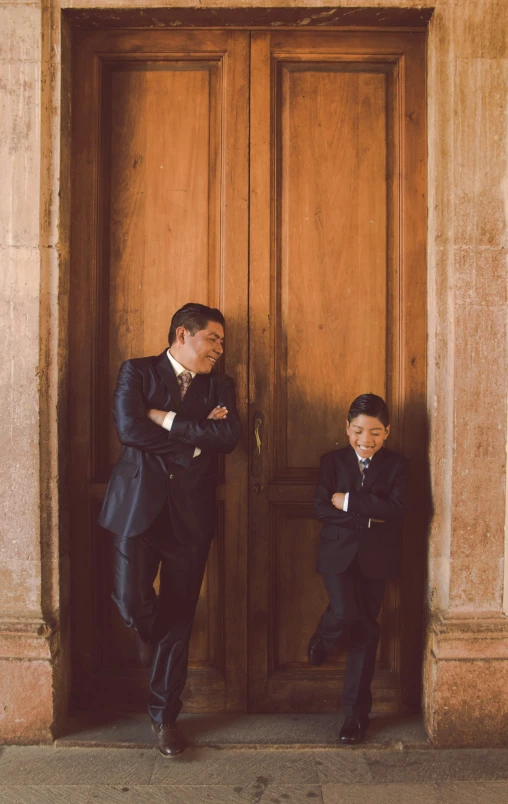 two men in suits standing on an entrance of a building