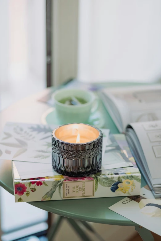 the candle is lit sitting on a stack of books