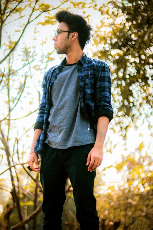 a young man standing with sunglasses on while wearing glasses