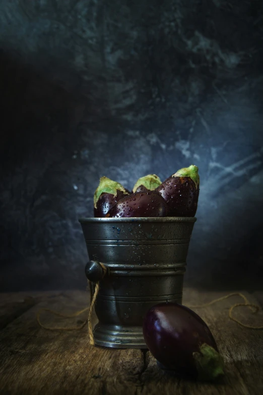 a metal bucket filled with fruit on top of a wooden table