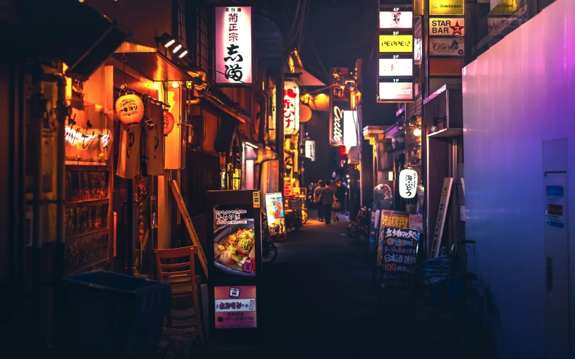 a dark alley is lit up with neon signs