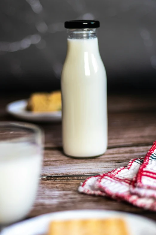 a bottle of milk on a table near cookies and ers