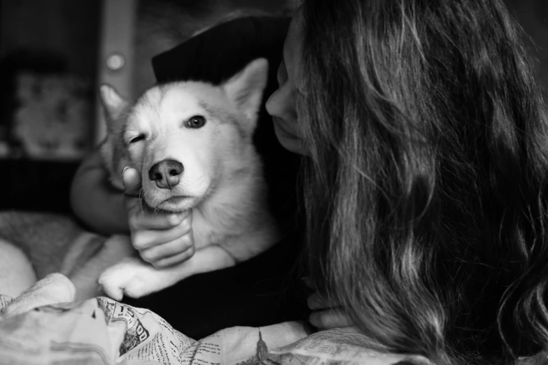 a woman is petting a dog that's laying on a bed