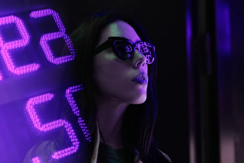 woman in neon glasses poses near a digital sign