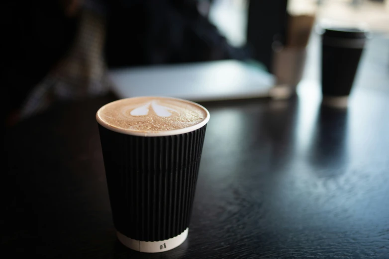 a tall cup of coffee with black plastic sleeves and a white lid