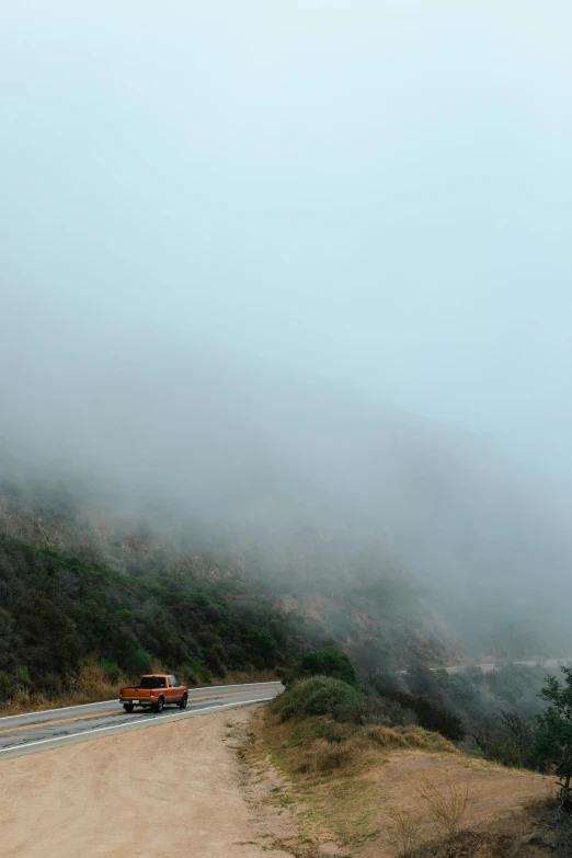 fog covering the mountains and a road with a car