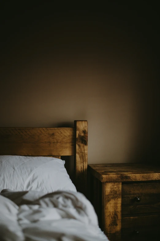 an unmade bed with white blankets sits against the wall in a dimly lit room