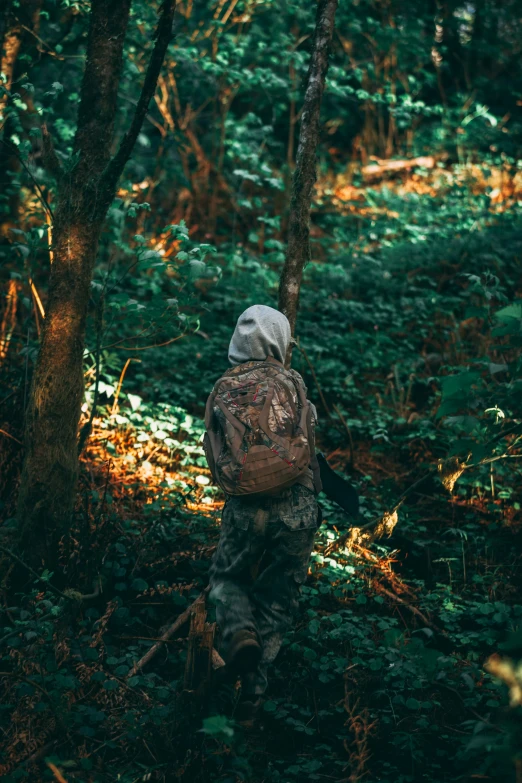 a man in camouflage clothing walks through a forest
