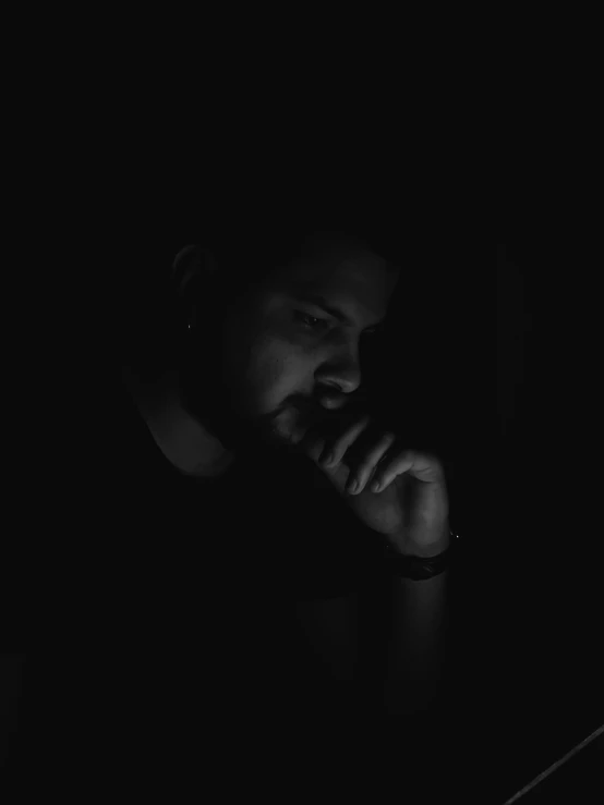 a man sitting in the dark with a laptop computer