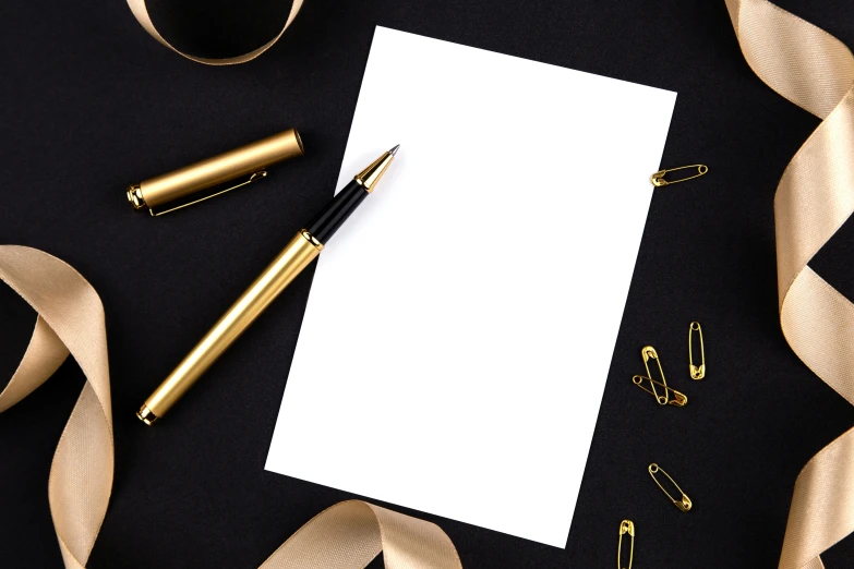 an overhead view of a notepad, pen and a pair of golden scissors